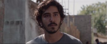 Movie still from “Lion” (2016), directed by Garth Davis – A person wearing a gray shirt; Close Up shot, Over the shoulder angle