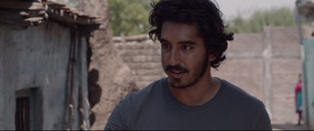 Movie still from “Lion” (2016), directed by Garth Davis – A person wearing a gray shirt; Close Up shot, Over the shoulder angle