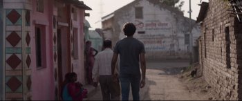 Movie still from “Lion” (2016), directed by Garth Davis – A group of people walking down a street; Wide shot, Low angle