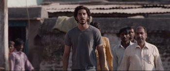 Movie still from “Lion” (2016), directed by Garth Davis – A man standing in front of another man; Medium shot, Low angle