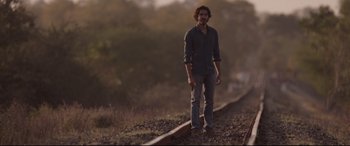Movie still from “Lion” (2016), directed by Garth Davis – A man standing on the side of a train track; Medium shot, Low angle