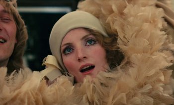 Movie still from “Lions Love (... and Lies)” (1969), directed by Agnès Varda – A person wearing a hat and a feather boa; Close Up shot, Low angle