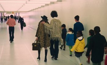 Movie still from “Lions Love (... and Lies)” (1969), directed by Agnès Varda – A group of people walking down a hall way; Wide shot, High angle