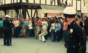 Movie still from “Lions Love (... and Lies)” (1969), directed by Agnès Varda – A crowd of people standing in front of a building; Wide shot, High angle