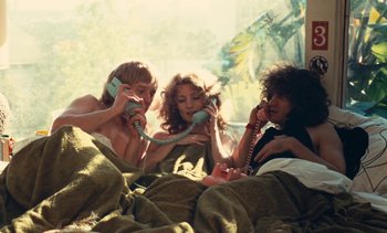 Movie still from “Lions Love (... and Lies)” (1969), directed by Agnès Varda – Three people sitting in a bed talking on phones; Medium shot, High angle