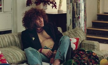 Movie still from “Lions Love (... and Lies)” (1969), directed by Agnès Varda – A man sitting on a couch with his shirt off; Medium shot, Low angle
