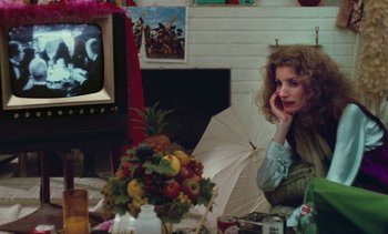 Movie still from “Lions Love (... and Lies)” (1969), directed by Agnès Varda – A woman sitting in front of a tv with an umbrella; Medium shot, High angle