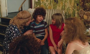Movie still from “Lions Love (... and Lies)” (1969), directed by Agnès Varda – A group of children sitting on a chair talking to each other; Medium shot, High angle