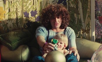 Movie still from “Lions Love (... and Lies)” (1969), directed by Agnès Varda – A woman sitting on a couch with a child; Medium shot, High angle