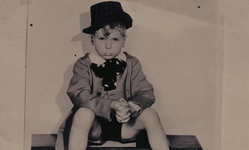 Movie still from “Lions Love (... and Lies)” (1969), directed by Agnès Varda – A young boy sitting on the ground wearing a suit and a hat; Medium shot, High angle