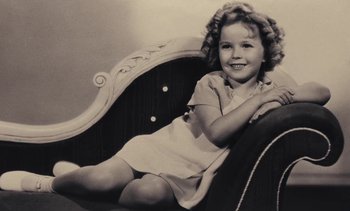 Movie still from “Lions Love (... and Lies)” (1969), directed by Agnès Varda – A little girl sitting in a chair smiling for the camera; Medium shot, High angle