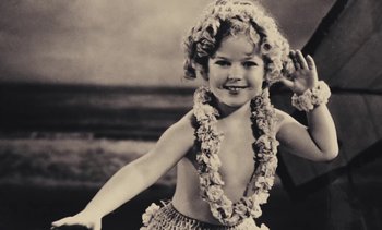 Movie still from “Lions Love (... and Lies)” (1969), directed by Agnès Varda – A little girl wearing a hula outfit and a lei around her neck; Close Up shot, High angle