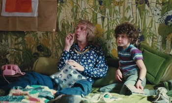 Movie still from “Lions Love (... and Lies)” (1969), directed by Agnès Varda – A man and a boy sitting on a couch in a room; Medium shot, High angle