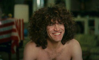 Movie still from “Lions Love (... and Lies)” (1969), directed by Agnès Varda – A man with a beard and curly hair smiling; Close Up shot, Over the shoulder angle