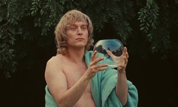 Movie still from “Lions Love (... and Lies)” (1969), directed by Agnès Varda – A shirtless man holding a crystal ball in his hands; Medium shot, Low angle