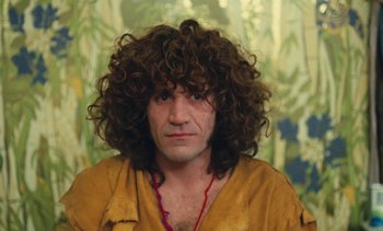 Movie still from “Lions Love (... and Lies)” (1969), directed by Agnès Varda – A man with long curly hair wearing a yellow shirt; Medium shot, Low angle