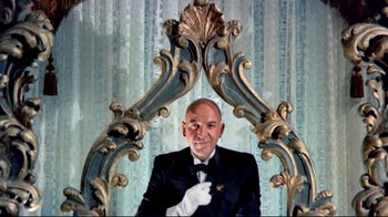 Movie still from “Lisa and the Devil” (1973), directed by Mario Bava – A man in a suit and tie sitting in front of a mirror; Medium shot, Low angle