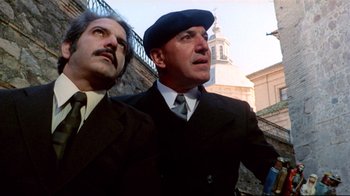 Movie still from “Lisa and the Devil” (1973), directed by Mario Bava – Two men in suits and hats looking up at the sky; Medium shot, Low angle