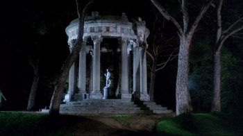 Movie still from “Lisa and the Devil” (1973), directed by Mario Bava – A statue of a person sitting in front of a gazebo at night; Extreme Wide shot, Low angle