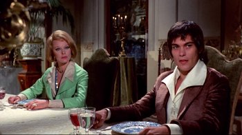 Movie still from “Lisa and the Devil” (1973), directed by Mario Bava – Two people sitting at a dinner table with a plate of food in front of them; Medium shot, Over the shoulder angle