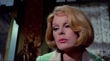 Movie still from “Lisa and the Devil” (1973), directed by Mario Bava – An older woman with blonde hair wearing a green jacket; Close Up shot, Over the shoulder angle