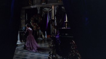 Movie still from “Lisa and the Devil” (1973), directed by Mario Bava – A woman in a purple dress standing in front of a piano; Wide shot, High angle