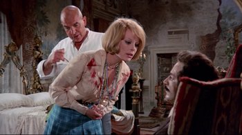 Movie still from “Lisa and the Devil” (1973), directed by Mario Bava – A man and a woman in front of another man in a room; Medium shot, Over the shoulder angle