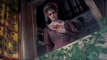 Movie still from “Lisa and the Devil” (1973), directed by Mario Bava – A woman in a purple dress holding her chest; Medium shot, Low angle