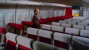 Movie still from “Lisa and the Devil” (1973), directed by Mario Bava – A woman standing in the aisle of an airplane; Wide shot, High angle