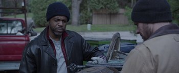 Movie still from “Wish Upon” (2017), directed by John R. Leonetti – A man sitting at a table outside in the day; Medium shot, Over the shoulder angle