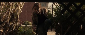 Movie still from “Wish Upon” (2017), directed by John R. Leonetti – A woman is crouching down near a bush; Medium shot, Low angle