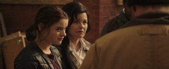 Movie still from “Wish Upon” (2017), directed by John R. Leonetti – Two women sitting next to each other in front of a brick wall; Close Up shot, Over the shoulder angle