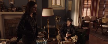 Movie still from “Wish Upon” (2017), directed by John R. Leonetti – A man and a woman sitting on a couch in a living room; Medium shot, Over the shoulder angle