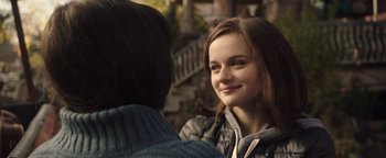 Movie still from “Wish Upon” (2017), directed by John R. Leonetti – A young girl smiling at a person sitting on a bench; Close Up shot, Over the shoulder angle