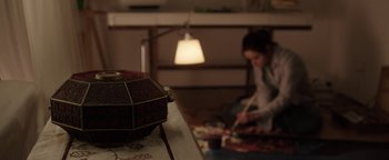 Movie still from “Wish Upon” (2017), directed by John R. Leonetti – A woman sitting on the floor in front of a lamp; Close Up shot, High angle