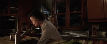 Movie still from “Wish Upon” (2017), directed by John R. Leonetti – A woman sitting at a counter in a kitchen; Medium shot, Low angle