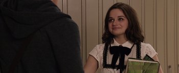 Movie still from “Wish Upon” (2017), directed by John R. Leonetti – A young woman wearing a white shirt and a black bow tie; Medium shot, Over the shoulder angle