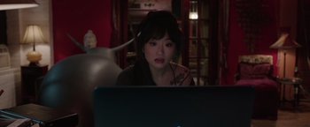 Movie still from “Wish Upon” (2017), directed by John R. Leonetti – A woman sitting in front of a laptop computer; Medium shot, High angle