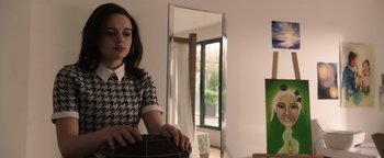 Movie still from “Wish Upon” (2017), directed by John R. Leonetti – A woman in a black and white shirt holding a chair; Medium shot, Over the shoulder angle