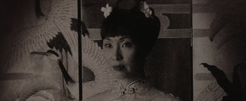 Movie still from “Wish Upon” (2017), directed by John R. Leonetti – An old photo of an asian woman in a cheongsam; Close Up shot, Low angle