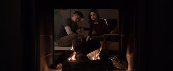 Movie still from “Wish Upon” (2017), directed by John R. Leonetti – A man and a woman sitting in front of a fireplace; Medium shot, High angle
