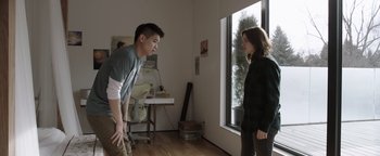 Movie still from “Wish Upon” (2017), directed by John R. Leonetti – A man and a woman in front of a large window; Medium shot, Over the shoulder angle