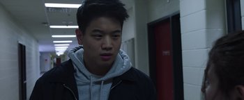 Movie still from “Wish Upon” (2017), directed by John R. Leonetti – A young man in a black jacket is looking at the camera; Close Up shot, Over the shoulder angle