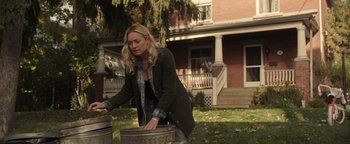 Movie still from “Wish Upon” (2017), directed by John R. Leonetti – A woman in a plaid shirt and a green jacket is by a trash can; Medium shot, Over the shoulder angle
