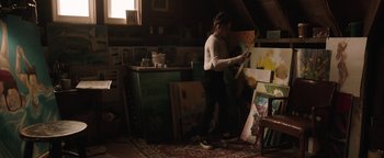 Movie still from “Wish Upon” (2017), directed by John R. Leonetti – A woman is painting in a cluttered room; Wide shot, Low angle