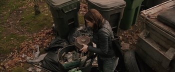 Movie still from “Wish Upon” (2017), directed by John R. Leonetti – A woman is picking up trash in a trash can; Medium shot, High angle