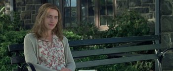 Movie still from “Little Children” (2006), directed by Todd Field – A woman sitting on top of a wooden park bench; Medium shot, Over the shoulder angle