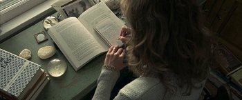 Movie still from “Little Children” (2006), directed by Todd Field – A woman is writing on a notebook while reading a book; Close Up shot, High angle