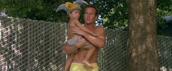 Movie still from “Little Children” (2006), directed by Todd Field – A man holding a boy in his arms outside; Medium shot, Low angle