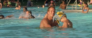 Movie still from “Little Children” (2006), directed by Todd Field – A man and a boy in a pool with people in the background; Close Up shot, High angle